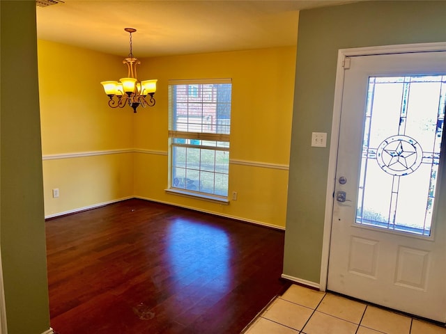 foyer entrance with tile patterned floors and an inviting chandelier