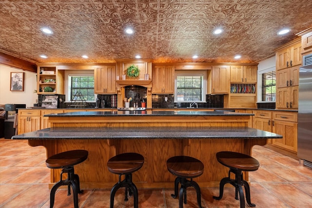 kitchen with stainless steel fridge, light tile patterned flooring, a breakfast bar area, and a center island