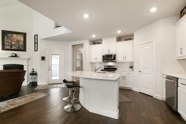 kitchen featuring appliances with stainless steel finishes, an island with sink, white cabinetry, and dark hardwood / wood-style floors