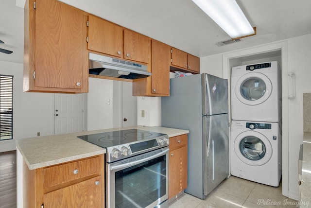 kitchen featuring kitchen peninsula, appliances with stainless steel finishes, stacked washing maching and dryer, and light tile patterned flooring