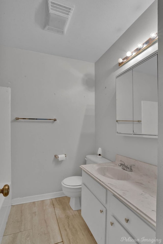 bathroom with toilet, vanity, and wood-type flooring