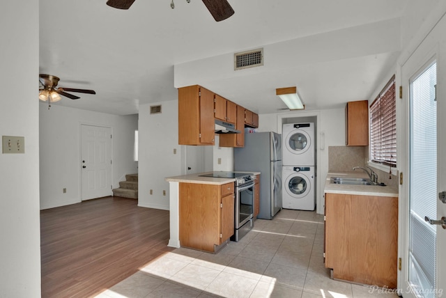 kitchen with stacked washer / drying machine, electric stove, tasteful backsplash, sink, and light tile patterned flooring