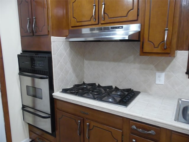 kitchen with decorative backsplash, black gas stovetop, and oven