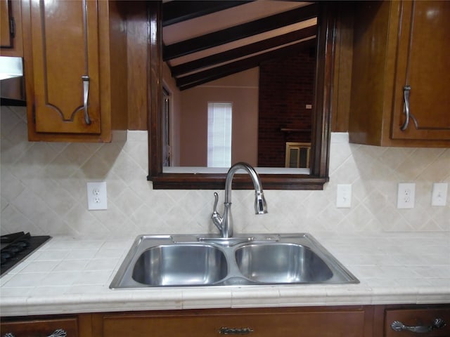 kitchen featuring lofted ceiling, tile countertops, decorative backsplash, and sink