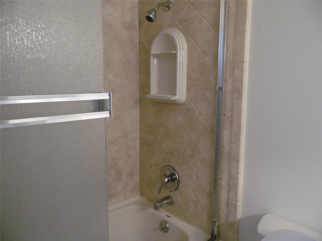 bathroom with toilet and tiled shower / bath