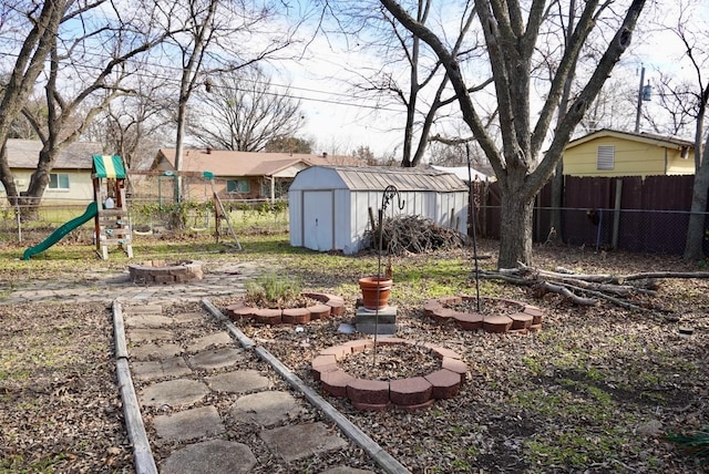 view of yard featuring a playground, a storage shed, and a fire pit