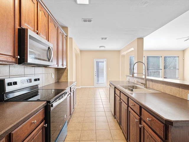 kitchen with light tile patterned floors, appliances with stainless steel finishes, sink, and a healthy amount of sunlight