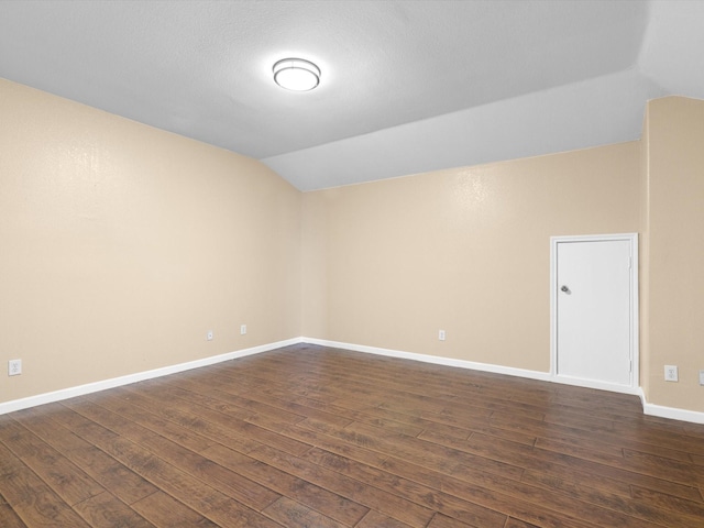 unfurnished room featuring dark hardwood / wood-style floors and vaulted ceiling