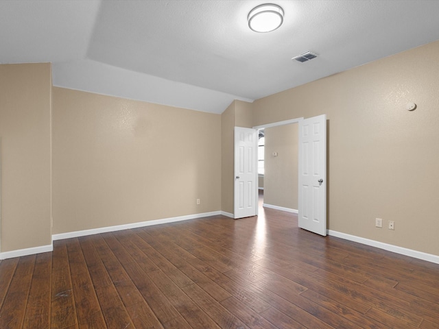 unfurnished room featuring vaulted ceiling and dark wood-type flooring