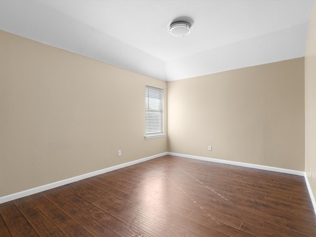 unfurnished room featuring dark hardwood / wood-style floors and vaulted ceiling