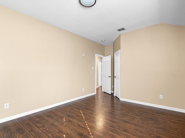 spare room featuring dark hardwood / wood-style floors and vaulted ceiling