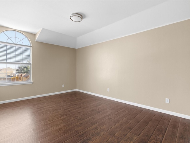 empty room featuring vaulted ceiling and dark hardwood / wood-style floors