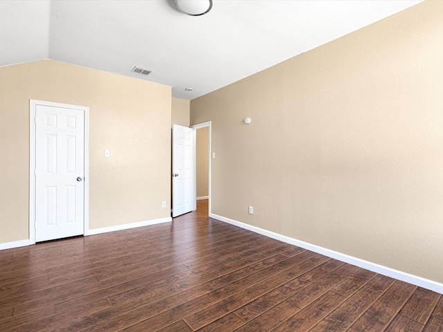 spare room featuring vaulted ceiling and dark hardwood / wood-style floors