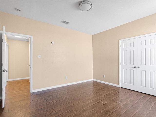 unfurnished bedroom with a closet and dark hardwood / wood-style floors