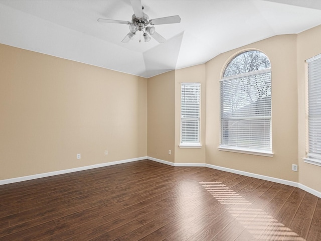 spare room with ceiling fan, dark wood-type flooring, and vaulted ceiling