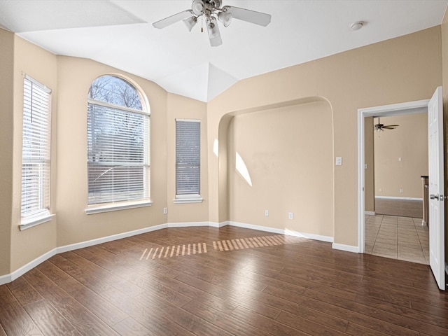 empty room featuring ceiling fan, vaulted ceiling, and dark wood-type flooring