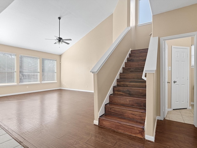 staircase with ceiling fan, a wealth of natural light, high vaulted ceiling, and hardwood / wood-style floors