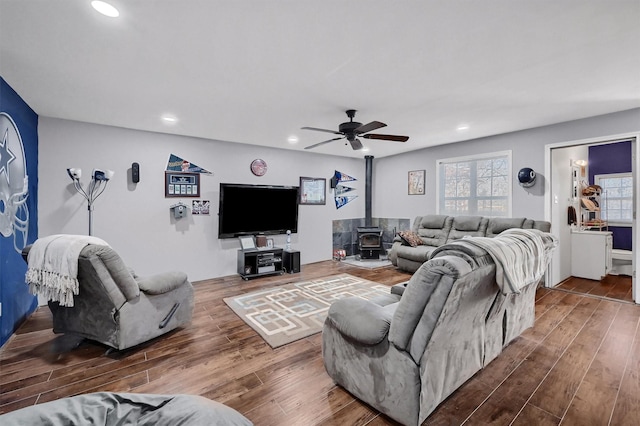 living room featuring a wood stove, ceiling fan, and hardwood / wood-style flooring