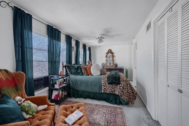 carpeted bedroom featuring ceiling fan, multiple windows, a closet, and a textured ceiling