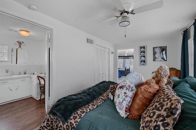 bedroom featuring ceiling fan, dark hardwood / wood-style flooring, sink, a textured ceiling, and a closet