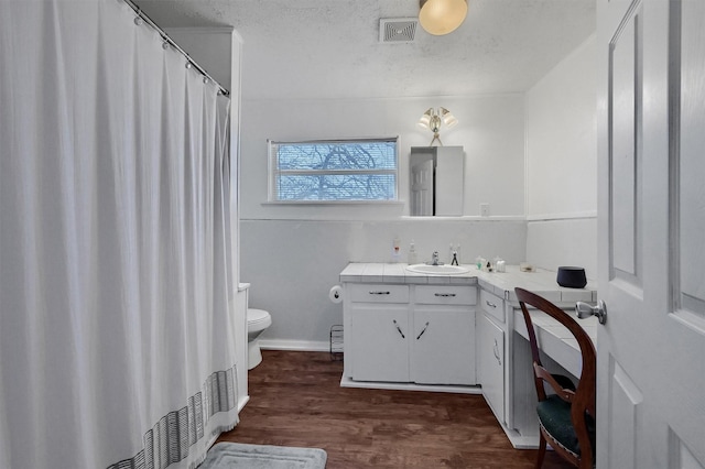 bathroom featuring wood-type flooring, toilet, vanity, and a textured ceiling