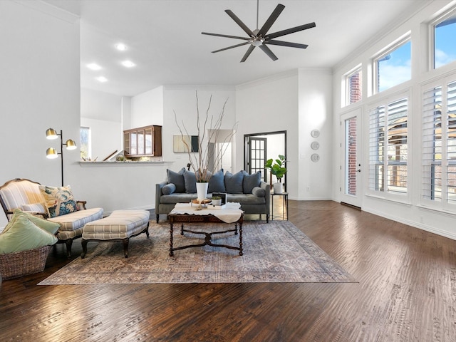 living room featuring ceiling fan, dark hardwood / wood-style floors, a wealth of natural light, and ornamental molding