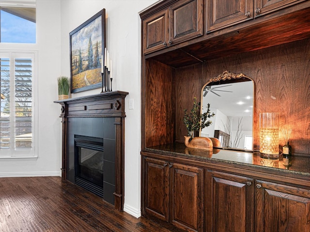 bar featuring a wealth of natural light, dark brown cabinets, dark stone countertops, and dark hardwood / wood-style floors