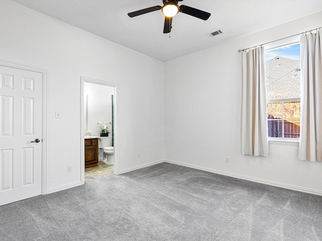 unfurnished bedroom featuring ceiling fan, light carpet, and connected bathroom