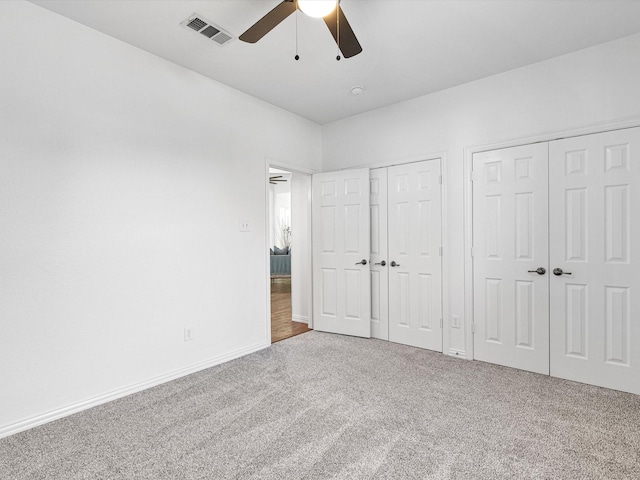 unfurnished bedroom with ceiling fan, carpet flooring, and two closets