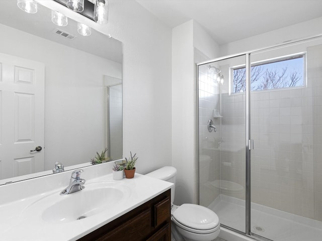 bathroom with toilet, vanity, and a shower with shower door