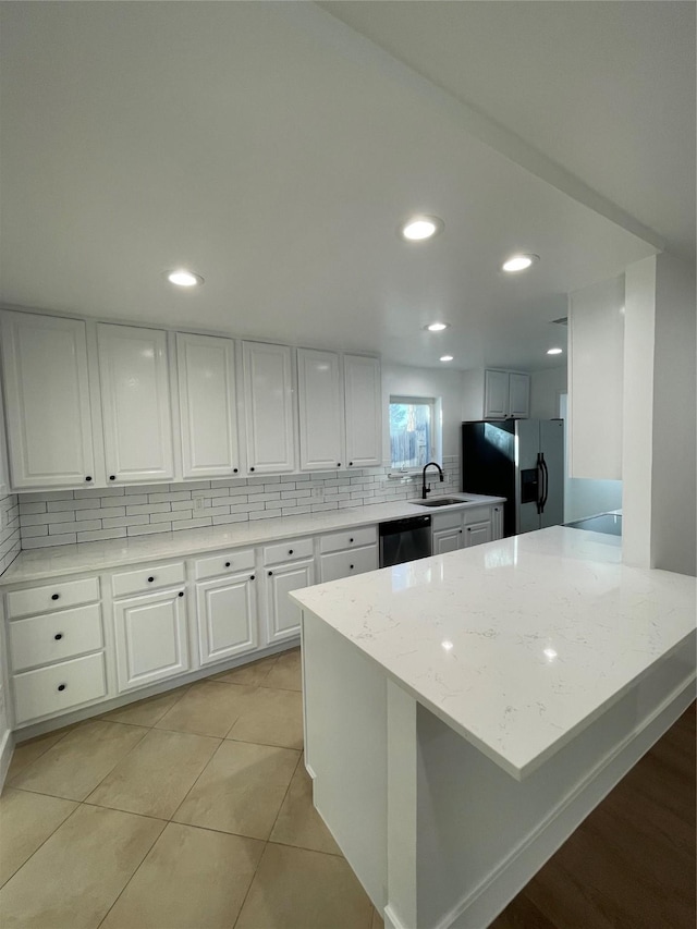 kitchen featuring light tile patterned floors, stainless steel appliances, tasteful backsplash, light stone countertops, and white cabinets