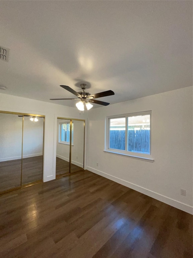 unfurnished bedroom with ceiling fan, dark hardwood / wood-style floors, and multiple windows