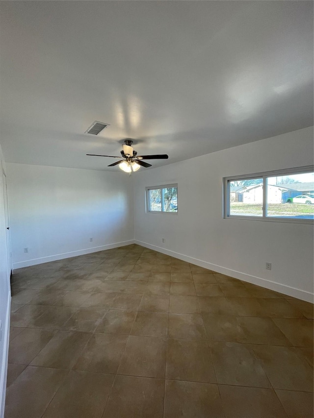 empty room with ceiling fan, tile patterned flooring, and plenty of natural light