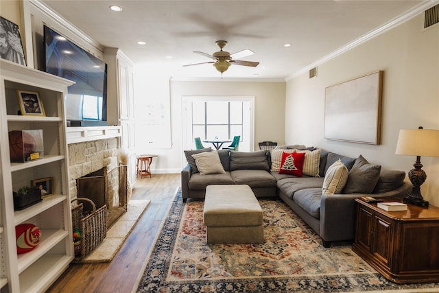 living room featuring ceiling fan, a fireplace, ornamental molding, and hardwood / wood-style flooring