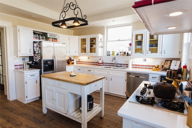 kitchen featuring white cabinetry, stainless steel appliances, sink, backsplash, and hanging light fixtures