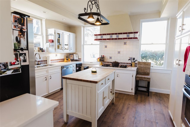 kitchen featuring decorative light fixtures, ventilation hood, white cabinetry, and a kitchen island