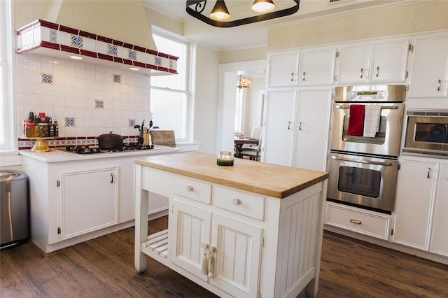 kitchen with decorative backsplash, white cabinetry, appliances with stainless steel finishes, and a kitchen island