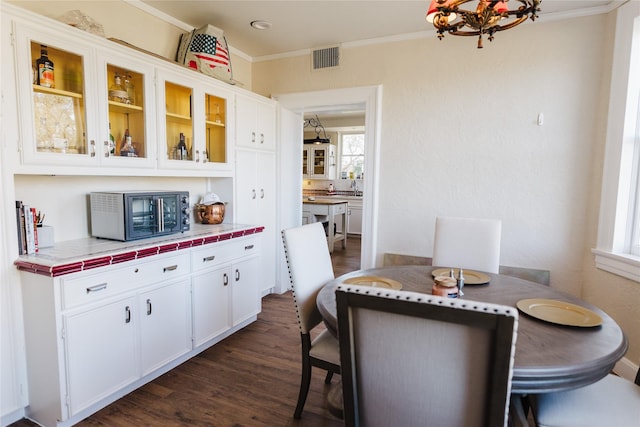 dining space with dark hardwood / wood-style flooring, sink, a chandelier, and ornamental molding