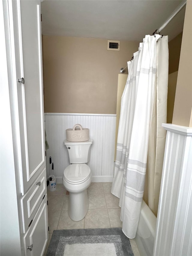 bathroom with toilet, shower / bath combo, and tile patterned floors