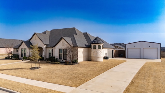 french country inspired facade featuring an outbuilding, a standing seam roof, concrete driveway, stone siding, and metal roof