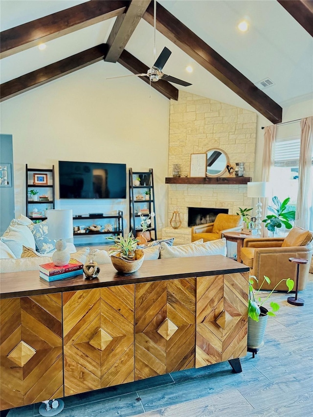 bar with wood finished floors, visible vents, a ceiling fan, lofted ceiling with beams, and a stone fireplace