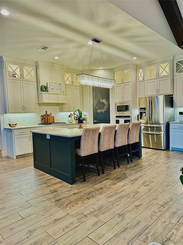 kitchen featuring decorative backsplash, stainless steel appliances, light wood-type flooring, and light countertops