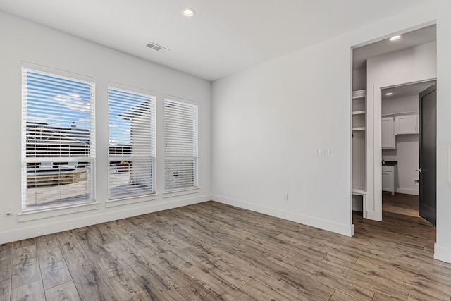 empty room with recessed lighting, visible vents, baseboards, and light wood finished floors