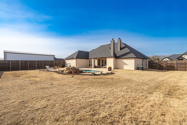 back of property with a patio area, a yard, a chimney, and a fenced backyard