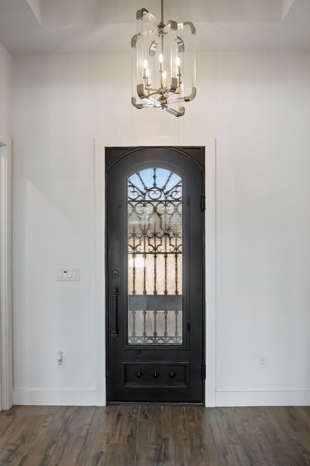 foyer entrance with a notable chandelier, baseboards, and wood finished floors