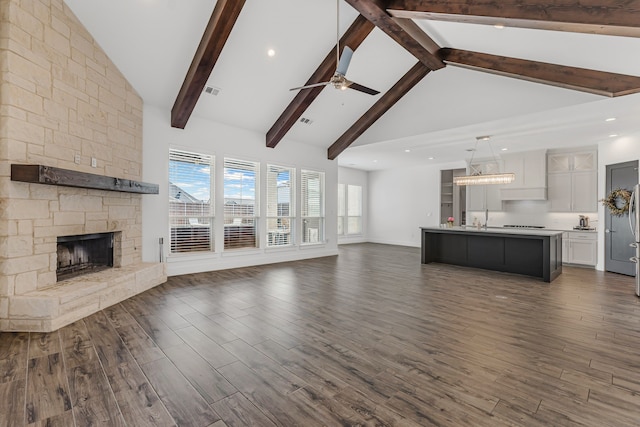 unfurnished living room featuring beam ceiling, high vaulted ceiling, a ceiling fan, a fireplace, and dark wood-style flooring