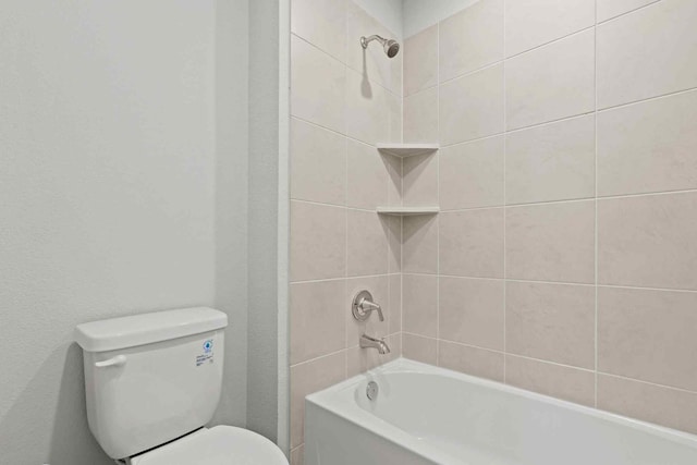 bathroom featuring tiled shower / bath combo and toilet