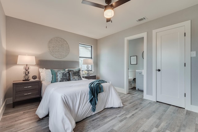 bedroom with ceiling fan, ensuite bathroom, and light hardwood / wood-style flooring