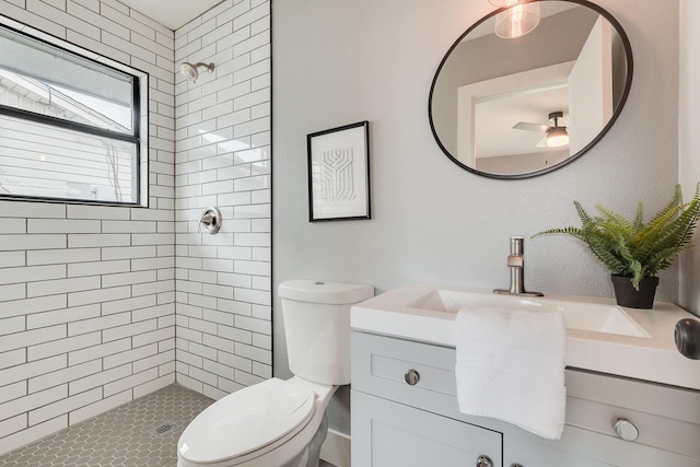 bathroom featuring toilet, vanity, and tiled shower