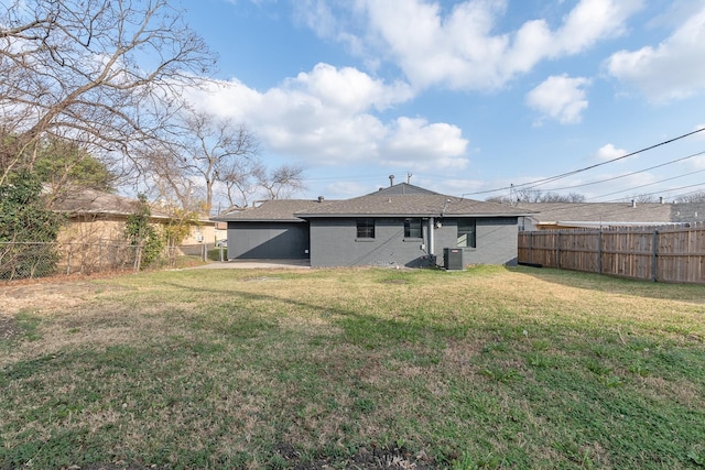 back of house with central AC unit and a yard